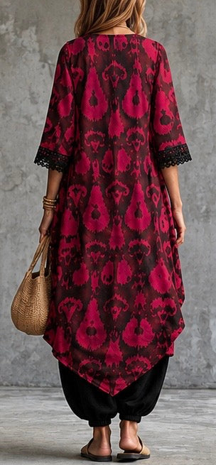 a loose, high-low tunic dress with a bold red and black paisley pattern, paired with black pants and sandals
